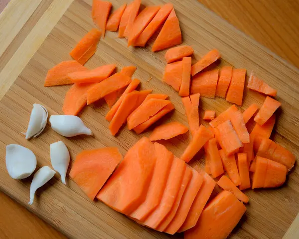 Taze doğranmış havuçlar ahşap bir tahtanın üzerinde, pişirilmeye hazır..