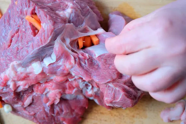 Yetenekli eller taze sebzeleri tahtadan kesilmiş bir et parçasına doldurur..