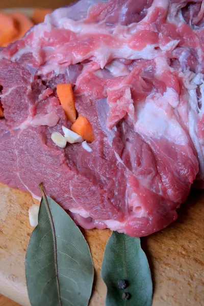 Taze et, sebze ve otlarla süslenmiş ahşap bir tahtanın üzerinde duruyor..