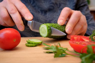 Ahşap bir tahtanın üzerinde ustaca kesilmiş salatalık ve domates..