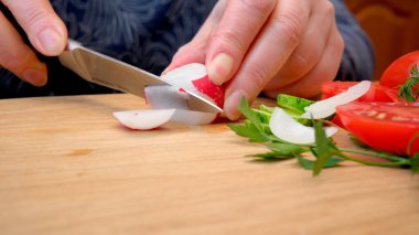 Eller ahşap bir tahtanın üzerinde turpları ve soğanları ustalıkla dilimler..