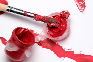 Bir fırça ve kap sanatsal ifadede kırmızı boyanın güzelliğini gösterir.