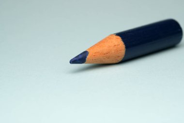 Keskinleştirilmiş mavi bir kalem yumuşak renkli bir yüzeye dayanır ve sanatsallığı davet eder..
