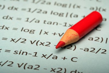 Karmaşık matematik denklemlerinde kırmızı bir kalemin yakın plan görüntüsü.