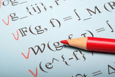 Kırmızı kalem matematik dersi sırasında mavi kağıt üzerinde önemli denklemleri vurgular.