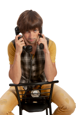 Genç bir birey, yaratıcı bir şekilde otururken iki adet klasik telefonla meşgul oluyor..