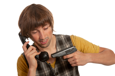 Ciddi bir ifadeye sahip genç bir adam telefonla iletişim kuruyor, silahı sıkıca tutuyor..