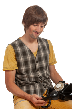 Retro giyinmiş bir adam sevgiyle eski bir telefonu inceliyor, gülümsüyor..