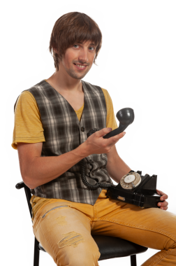 Gündelik giysiler içinde genç bir adam döner bir telefon tutuyor, davetkar bir şekilde gülümsüyor..