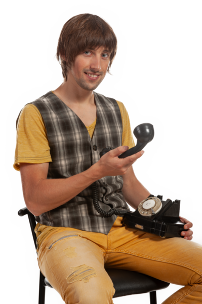 Gündelik giysiler içinde genç bir adam döner bir telefon tutuyor, davetkar bir şekilde gülümsüyor..