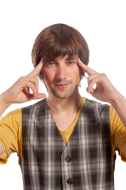 Ekose bir yelek giyen bir adam şakacı bir şekilde poz verir, elleri şakaklarında, parlak bir şekilde gülümser..