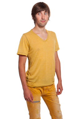 Genç bir adam, parlak sarı bir kıyafet giyerken kafası karışmış bir ifadeyle ayakta duruyor..