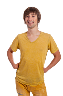 Genç adam, elleri kalçasında, parlak sarı bir gömlek ve kot pantolon giymiş mutlu bir şekilde ayakta duruyor..