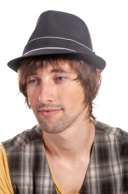 Fötr şapkalı bir insan parlak stüdyo ışıklarında düşünceli bir şekilde bakar..