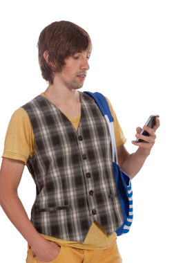 Genç bir adam elinde akıllı bir telefonla dikiliyor, çelik yelek ve tişört giymiş..