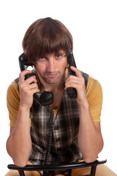 Genç bir adam otururken iki eski telefonla hokkabazlık yapıyor, kafası karışmış bir ifade sergiliyor..