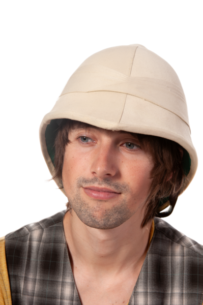 Özel bir şapka takan genç bir adam ekose kıyafetini sergilerken hafifçe gülümsüyor..