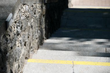 Parlak sarı çizgiler, doğayla çevrili gölgeli taş bir merdivenden aşağıya doğru yol gösteriyor..