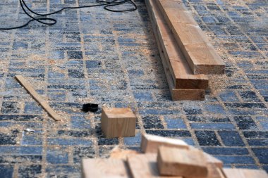 Ağaç talaşlarıyla kaplı bir atölye zemininde kereste katları düzenlenir..