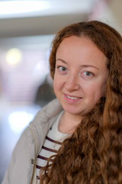 Kıvırcık saçlı neşeli genç bir kadın, dostça bir iç mekanda eğleniyor.