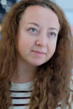 Kıvırcık kahverengi saçlı bir kadın derin bir sohbete dalmış, merakını belli ediyor..