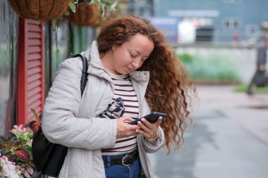 Genç bir kadın yağmurlu bir şehir kaldırımında bir anlık bağlantının keyfini çıkarıyor..