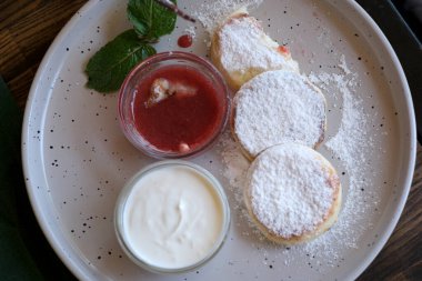 Tatlı krepler ahududu sosu ve kırsal bir tabakta çırpılmış kremayla servis edilir..