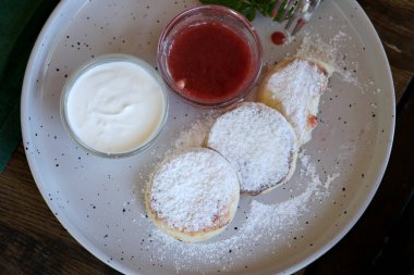 Kırsal bir tabakta toz şekere bulanmış krep ve yanında böğürtlen sosu..