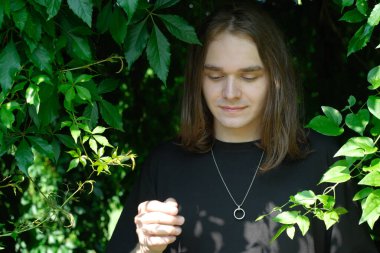 Genç bir insan, zengin yeşilliklerle çevrili olarak huzurla ayakta duruyor, huzurun tadını çıkarıyor..