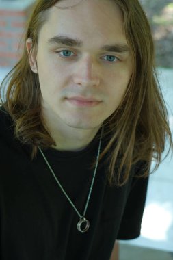 Düşünceli genç bir adam dışarıda oturur, doğayla iç içe, sıcak güneş ışığı altında..