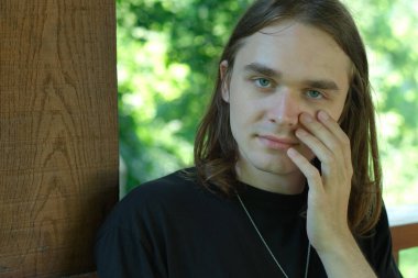 Genç bir adam düşüncelere dalmışken nazikçe yüzüne dokunur..