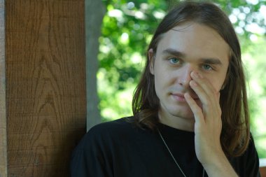 Genç insan sessizce yansıyor, elini yüzüne koyuyor, doğanın sükunetiyle çevrili..