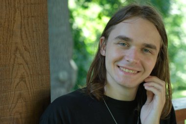 Neşeli genç bir adam doğanın sıcaklığından zevk alırken usulca gülümsüyor..