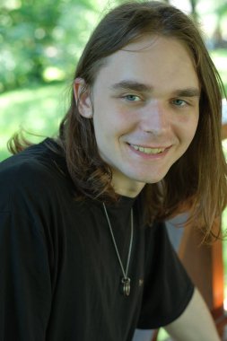 Neşeli genç bir adam yemyeşil yemliklerle çevrili güneş ışığının tadını çıkarıyor..