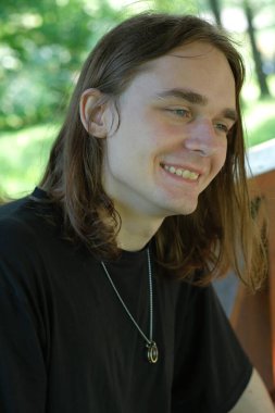 Gülümseyen genç adam, doğa ve kahkahalarla çevrili açık havada rahatlar..