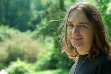 Genç bir insan neşeli bir doğayla gülümsüyor, sükunetin tadını çıkarıyor..