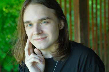 Uzun saçlı genç bir adam doğayla çevrili huzurlu bir anın tadını çıkarır..