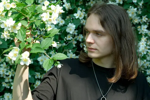 Genç bir adam renk dolu canlı bir bahçede çiçeklere hayran..