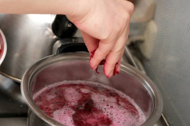 El dikkatle böğürtlenleri ocakta kaynayan kaba sıkıyor ve reçel oluşturuyor..