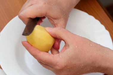 Eller ustalıkla canlı bir patatesi soyar, lezzetli bir yemeğe hazırlanır..