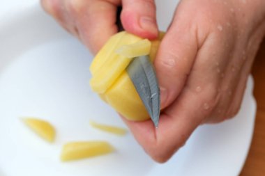 Eller ustalıkla taze patatesleri sıcaklıkla dolu güneşli bir mutfakta soyarlar..