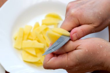 Eller ustalıkla çiğ patatesi dilimlere ayırır. Yemek pişirmek, dikkat çekmek için..