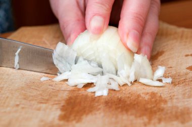 Elleri becerikli bir şekilde soğan doğruyor, yemek hazırlarken güzel kokulu aromalarını salıyor..