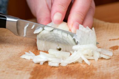 Samimi bir mutfakta ahşap bir kesme tahtasıyla soğanları ince ince dilimlemek..