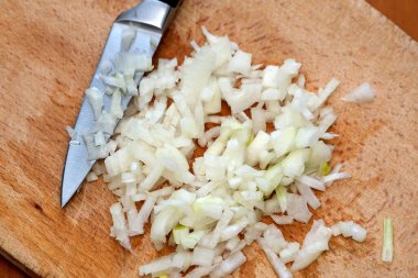 Yetenekli bir eller evdeki tahta bir tahtanın üzerinde hassasiyetle soğan doğruyor..