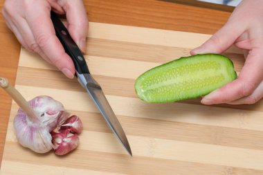 Taze salatalık ve sarımsağı lezzetli bir yemek için ustalıkla hazırlar..