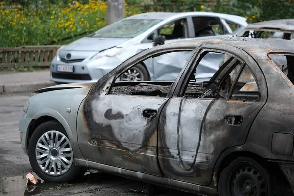 Zarar görmüş ve yanmış araçlar kasvetli bir şehir ortamında cadde boyunca dizilmiş, anıları canlandırıyor..