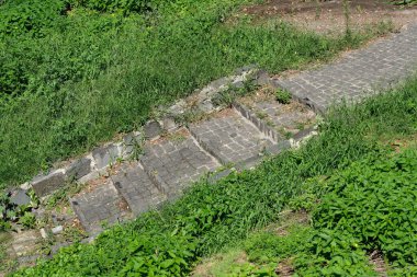 Bir zamanlar kullanılan kaldırım taşı yolu şimdi kalın yeşil çimlerin altında saklı..