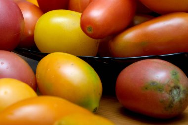 Olgun domateslerin renkli çeşitleri bir kaseyi doldurur, neşeli bir ziyafeti davet eder..