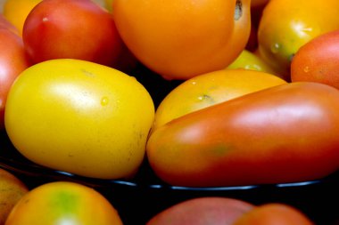 Koyu bir kasede bir dizi taze domates..